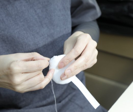 パフの口の部分を手縫いで仕上げる内職の作業の様子